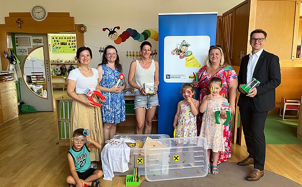 Übergabe der Sumsi-Forscherbox an den Kindergarten Steinbrunn: Aniko Benkö, Geschäftsführerin der Industriellenvereinigung Burgenland, Kerstin Beiglböck, Leiterin Kindergarten Steinbrunn, Madelaine Ribits, Leiterin Kindergarten Steinbrunn, Isabella Radatz-Grauszer, Bürgermeisterin und Volksschuldirektorin Steinbrunn, sowie Rudolf Suttner, Vorstandsdirektor der Raiffeisenlandesbank Burgenland, mit drei jungen Forscher*innen.